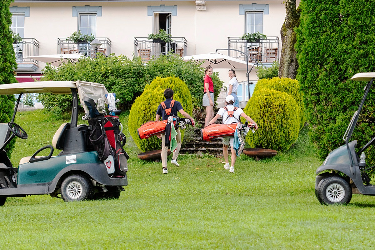Golfisti con sacche e golf cart davanti alla Club House di Asiago