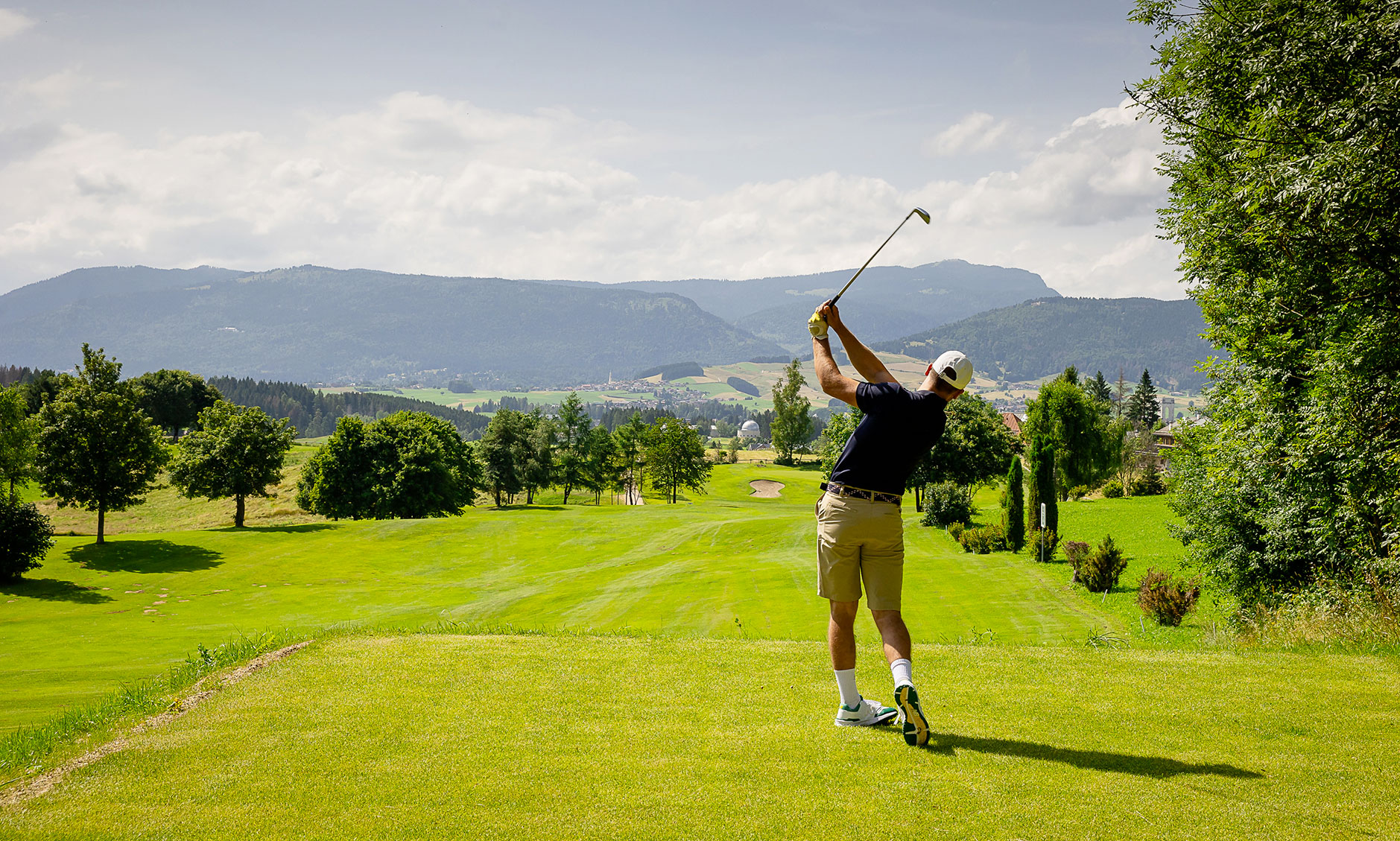 Golfista in swing sul fairway del Golf Club Asiago con vista sulle montagne